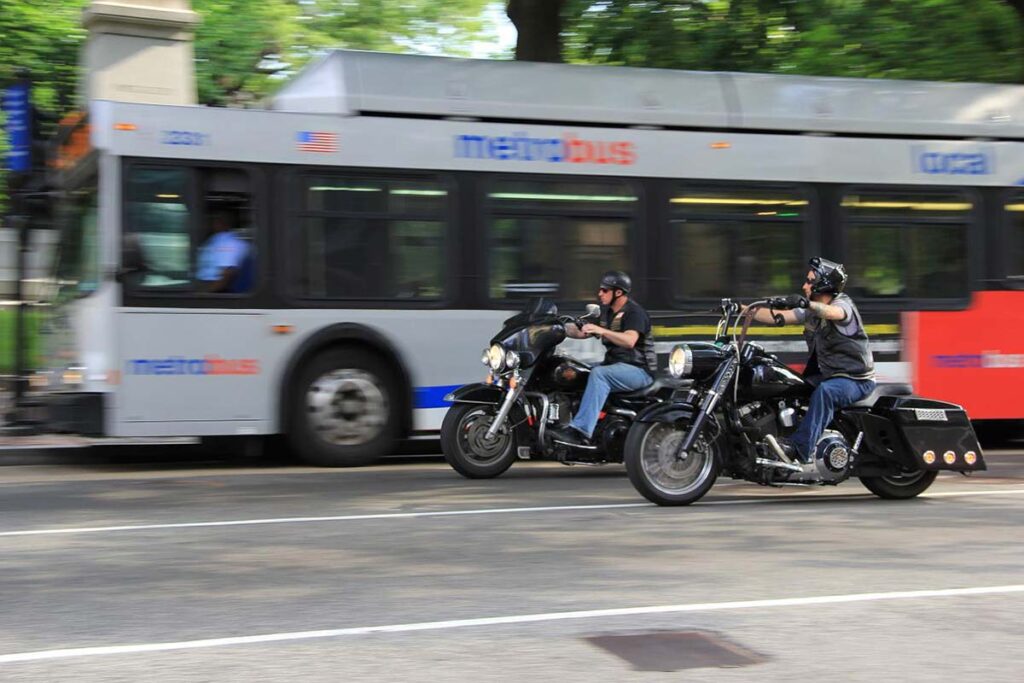 Harley Davidson Motorcycles Riding Next to Bus