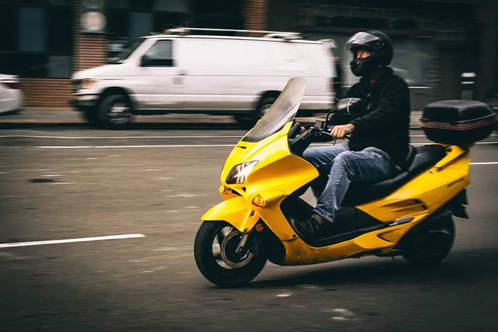 Person Riding a Yellow Motor Scooter