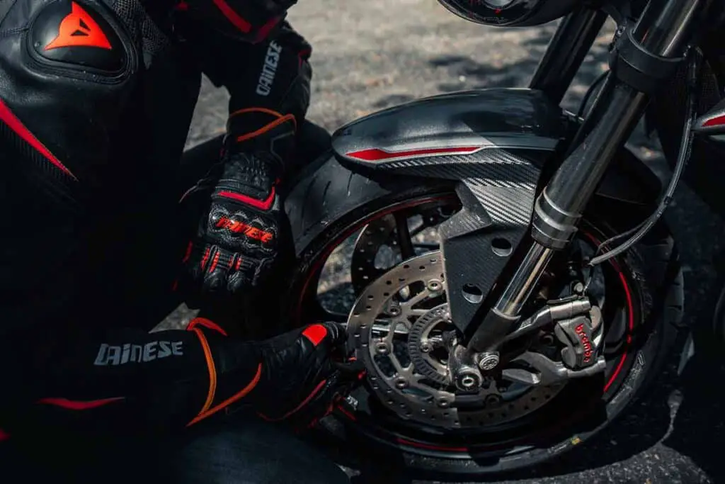 Motorcycle Rider Inspecting Front Wheel