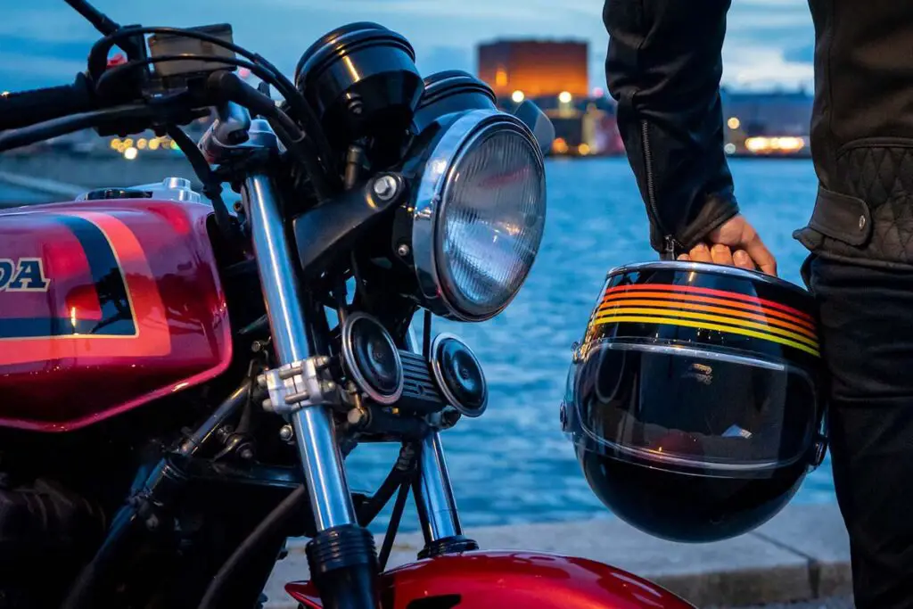 Person Holding Helmet Standing Beside Red Honda Motorcycle